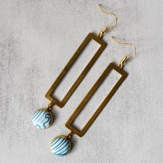 Catch some beach vibes with our Sandy Beaches Earrings! These blue and gold beauties feature a fun ocean print and a long rectangle charm. Perfect for adding a touch of seaside charm to any outfit. Due to the handmade nature of this product, no two earrings are exactly the same. Product Details 3.5" long x 0.75" wide Gold plated french hooks, nickel free Raw brass charm Gold plated pendant tray Glass cabochon Cotton fabric Care Instructions Keep earrings dry, remove when cleaning or near water. Clean with a soft cloth. Store in a dry, enclosed container. Handmade Fabric Earrings, Diy Soda, Cold Connections, Two Earrings, Cloth Store, Magnetic Earrings, Beach Earrings, Fabric Earrings, Gold Beauty