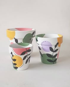 three cups with different designs on them sitting next to each other in front of a white background