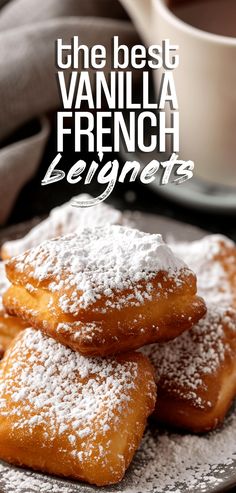 three powdered sugar covered doughnuts on a plate next to a cup of coffee