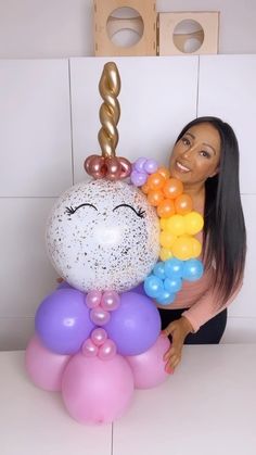 a woman is holding balloons in front of her face and an unicorn balloon on top