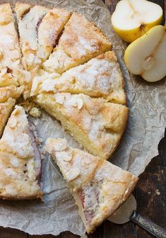 an apple pie is cut into slices on a piece of wax paper next to sliced apples