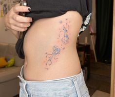 a woman with a tattoo on her stomach holding a cell phone in her right hand