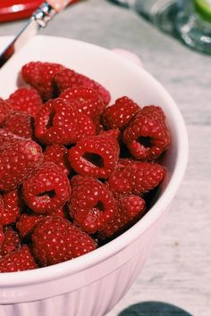 a bowl full of raspberries sitting on a table