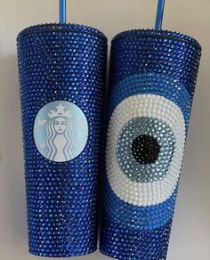 two cups with blue and white designs on them, one has an evil eye in the middle