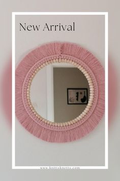 a pink mirror hanging on the side of a wall next to a white framed photo