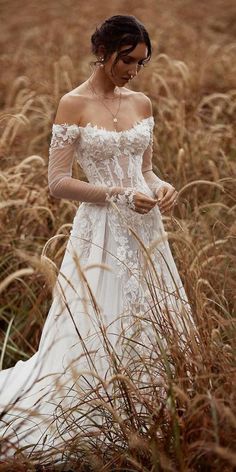 a woman in a white dress standing in tall grass