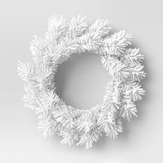 a white christmas wreath with snow flakes hanging from it's sides on a gray background