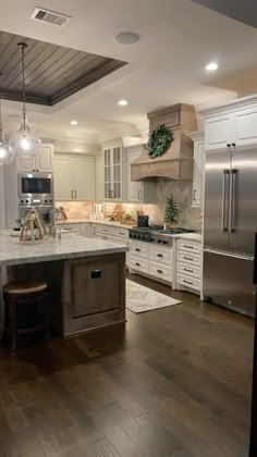 a large kitchen with white cabinets and wood floors