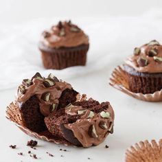 three cupcakes with chocolate frosting and sprinkles on white paper