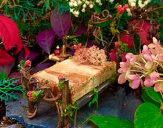 a small wooden bench surrounded by flowers and greenery with the words family tree miniatures on it