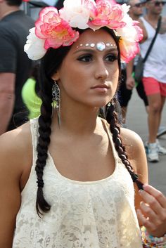 a woman with flowers in her hair wearing a white top and pink flower headband