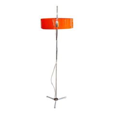 a floor lamp with an orange shade on the top and silver base, against a white background