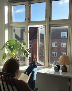 a woman is sitting in a chair looking out the window with her feet propped up