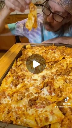 an old man is eating some food out of a casserole dish on the table