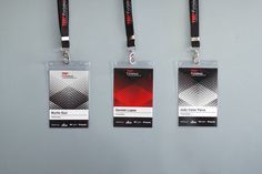 three lanyards are hanging on the wall with black and red tags attached to them