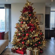 a decorated christmas tree in a living room with red and gold ornaments on the top