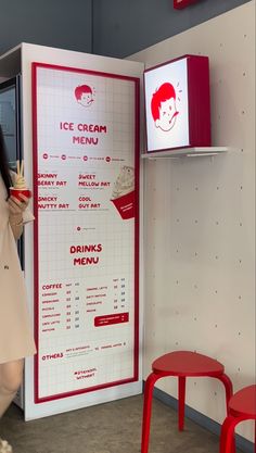 a woman standing in front of a red and white ice cream menu with drinks on it