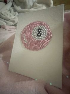 a card with a button on it sitting on top of a pink fur covered bed