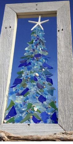 a christmas tree made out of sea glass is displayed in a frame with a starfish on top