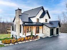 a large white house with a black roof and two garages in front of it