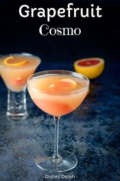 two glasses filled with drinks sitting on top of a blue counter next to lemons