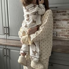 a woman holding a baby in her arms while standing next to a kitchen counter top