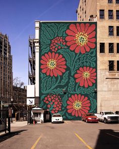 a large mural painted on the side of a building with red flowers and green leaves