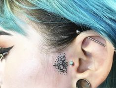 a woman with blue hair has a tattoo on her ear