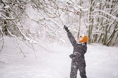 a person standing in the snow throwing a frisbee to another person who is reaching for it