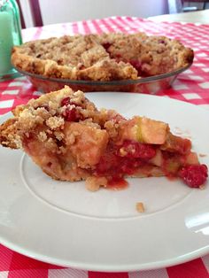 a piece of pie sitting on top of a white plate next to a bowl of fruit