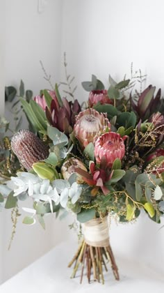 a bouquet of flowers sitting on top of a white table next to a mirror and wall