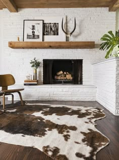 a living room with a white brick fireplace and cow hide rug