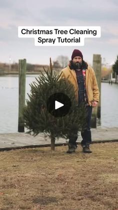 a man standing next to a christmas tree on top of a wooden pier near the water