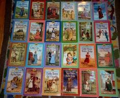 many children's books are arranged on the floor in front of a quilted blanket