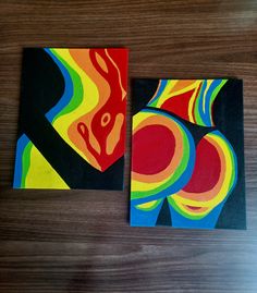 two square paintings on a wooden table with one painted in different colors and the other made out of wood