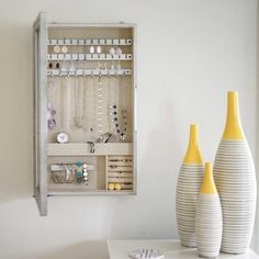 two white vases sitting next to each other on top of a table in front of a wall