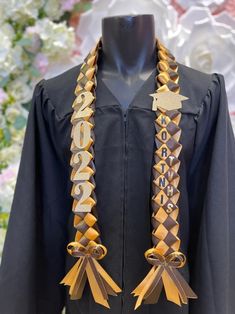 a black graduation gown with gold letters and tassels