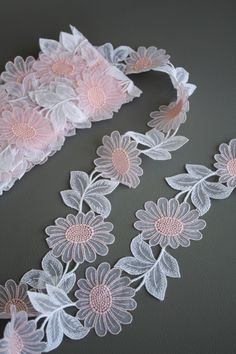 white lace with pink flowers and leaves on grey tablecloth, next to headband