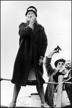 an old black and white photo of two women standing on a boat, one holding something in her hand