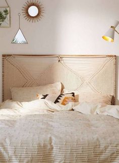 a bed with white sheets and pillows in a bedroom next to two wall lamps on either side of the headboard