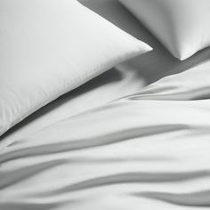 a bed with white sheets and pillows in black and white photo taken from the side