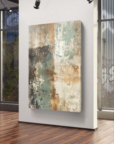 an abstract painting hangs on the wall next to a wooden floor in front of a large window