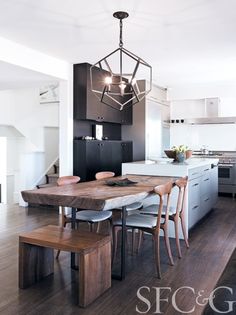 a modern kitchen with an island and dining table in the center, surrounded by wooden flooring