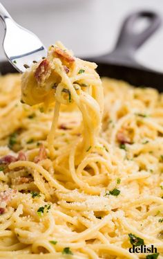 a fork full of spaghetti being lifted from a skillet