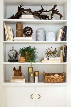 a white book shelf filled with lots of books and vases on top of it