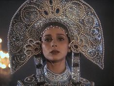 a woman wearing an elaborate head piece with pearls on it's face and eyes