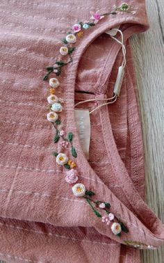 a pink shirt with flowers on it laying on top of a wooden floor next to a piece of string