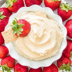 a platter filled with strawberries and dip on top of a white table cloth