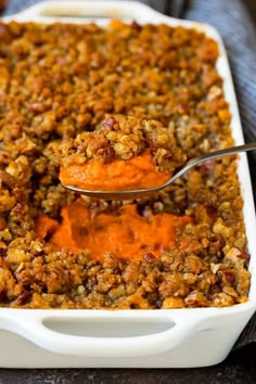 a spoonful of sweet potato casserole is being lifted from the casserole dish