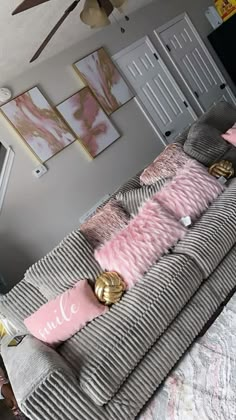 a living room filled with lots of furniture and pink pillows on top of the couch